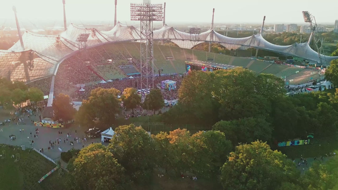 Olympiastadion München, Nahaufnahmen von tanzenden und singenden Menschenmengen und Künstler*innen, gute Laune, Pride-Flaggen, im Dunkeln Bühneneffekte mit Licht und Feuerwerk
